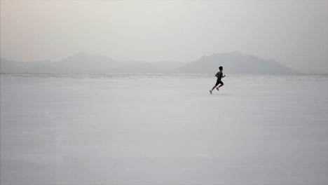 Dramatic-aerial-of-young-boy-running-in-Utah-desert-salt-flat