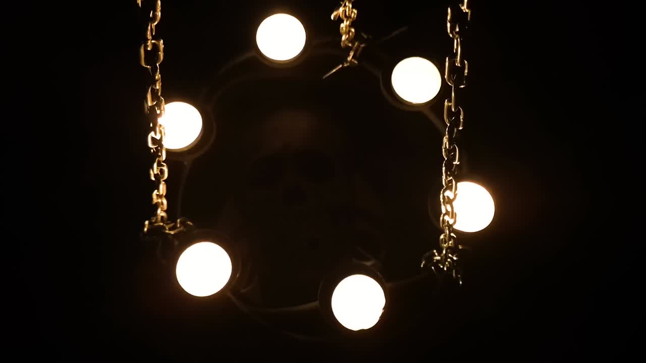 манекен человеческого черепа, окруженный свечами на цепях