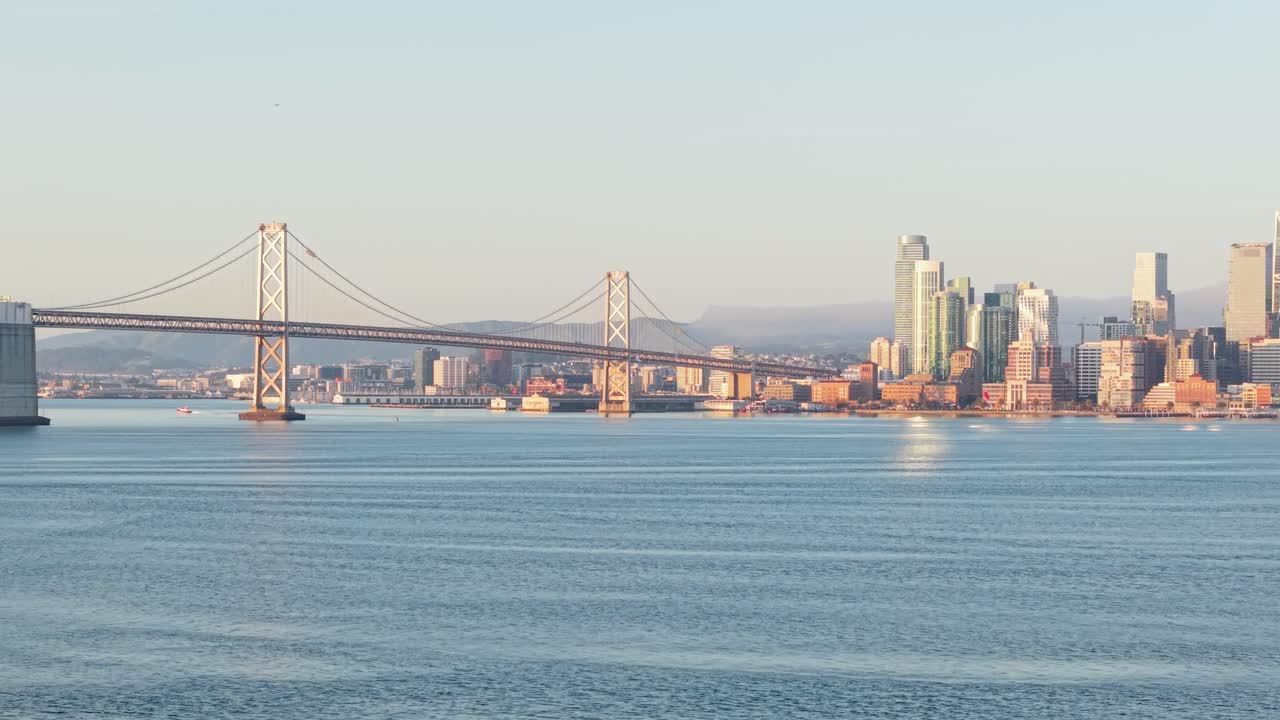Skyscrapers stand tall over Embarcadero’s piers as the sun glints off rooftops and the bay sparkles nearby.