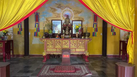 santuario dentro del templo budista guan di en hoi an, vietnam con cortinas amarillas retiradas