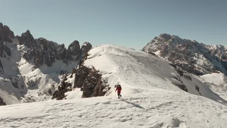 Toma-Cinematográfica-De-Un-Senderista-Caminando-Por-Una-Empinada-Cresta-Nevada