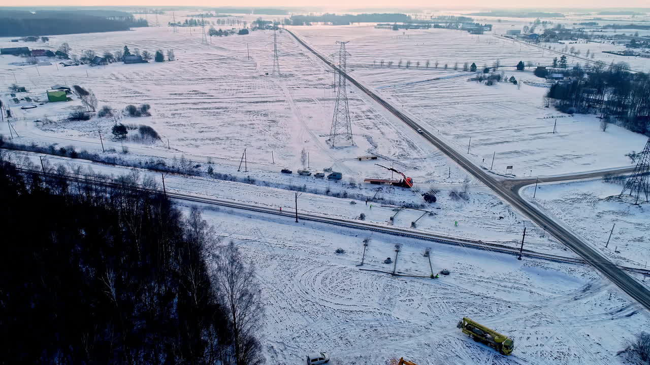 서로 가까이 있는 유럽 도로와 철로의 영화적 공중 촬영과 눈과 극적인 하늘로 뒤덮인 광활한 풍경