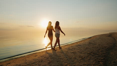 Joven-Madre-Con-Su-Hija-Un-Adolescente-Caminando-Por-La-Playa-Al-Atardecer-Vista-Posterior