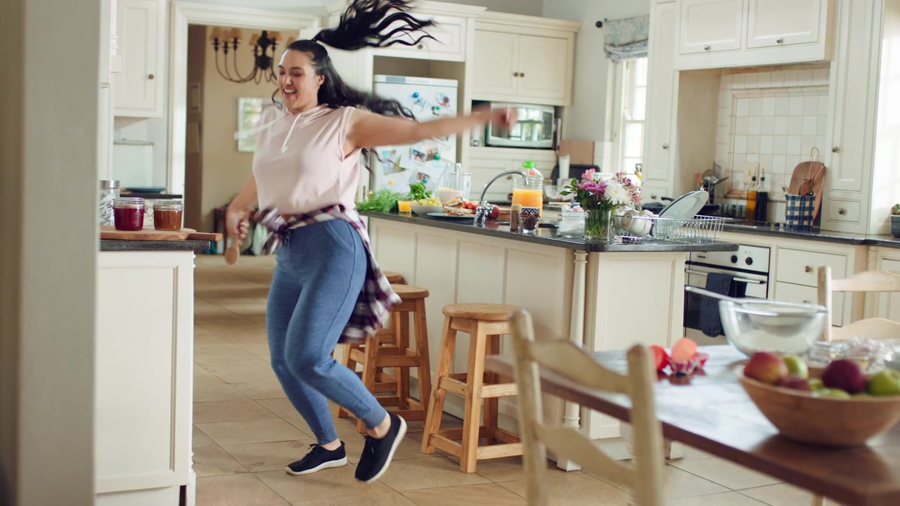 Young Woman Dancing Energetically in a Bright Kitchen