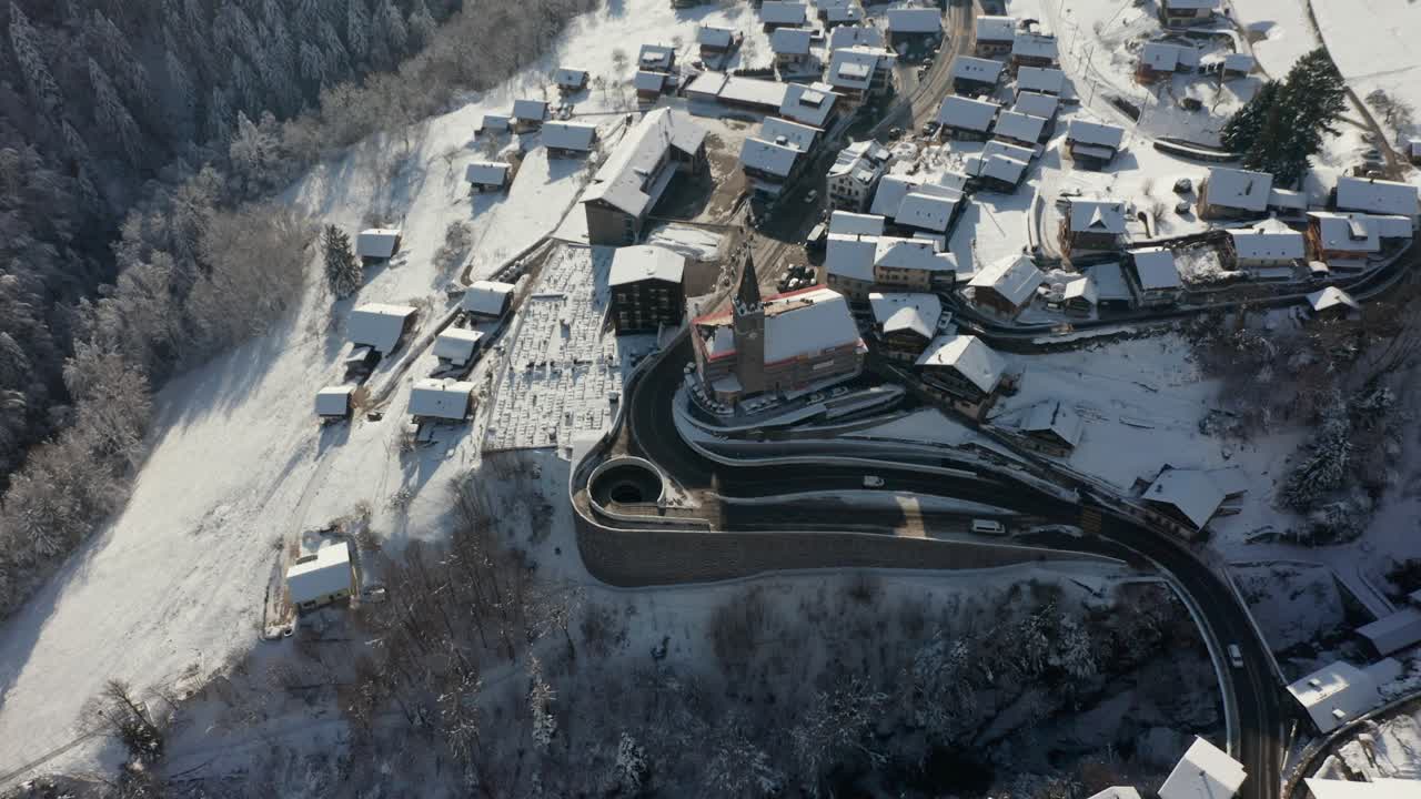 drone volando lejos de la iglesia y revelando un hermoso pequeño pueblo de montaña en invierno
