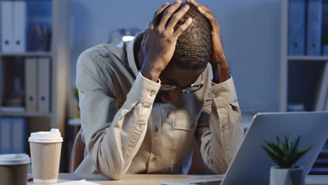 Joven-Oficinista-Hombre-Enojado-Y-Nervioso-Con-Anteojos-Trabajando-En-La-Computadora-Portátil-En-La-Oficina-Por-La-Noche