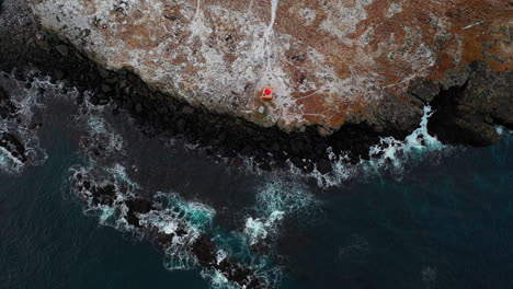 faskrudsfjordur, fjarðabyggð, east iceland - an orange lighthouse in a rocky island somewhere in the village of faskrudsfjordur - drone footage