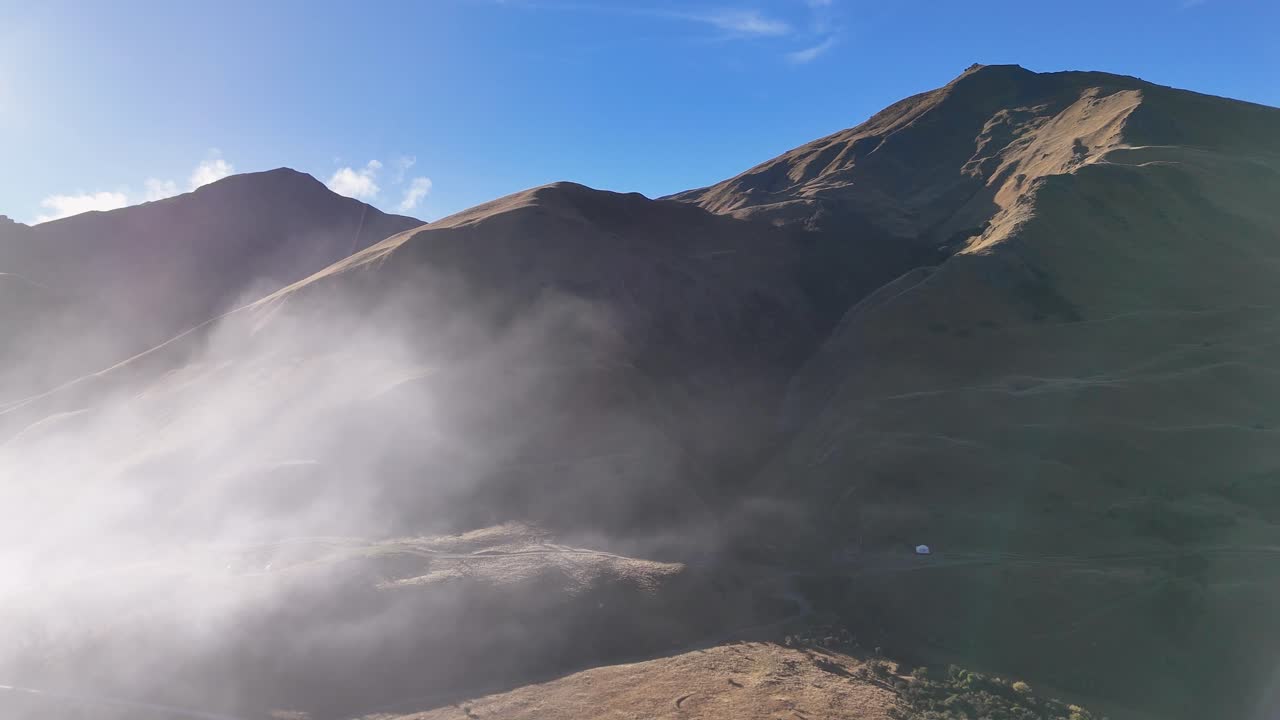 Aerial view of mountains enveloped in mist, captured by drone in bright daylight