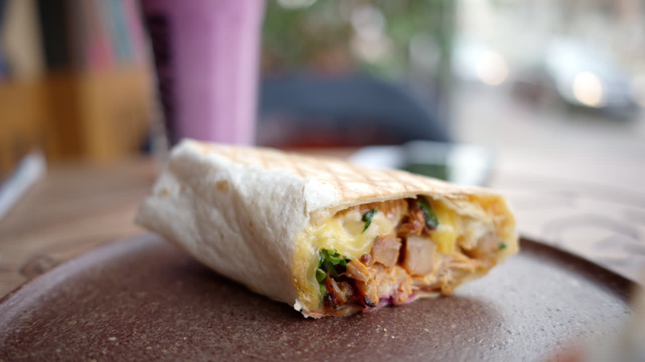 Close-up of cut up wrap on the table, with a smoothie on the background