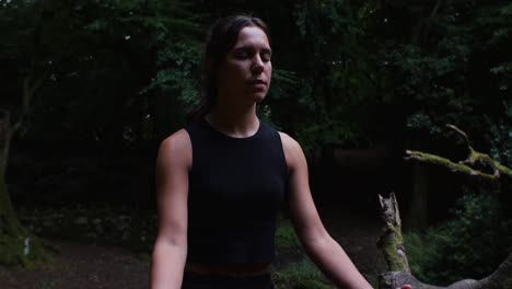 mujer joven centrándose en la respiración durante la sesión de meditación del bosque