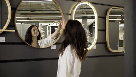 woman intently examines face in compact mirror lying on bed