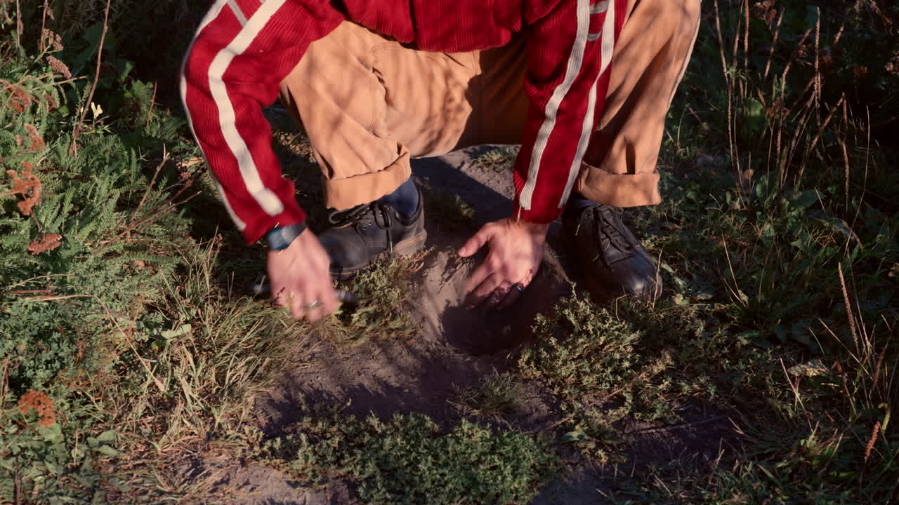 A symbolic close-up of a person burying a smartphone in the ground, representing digital detox, mindfulness, freedom from technology addiction, and reconnection with nature