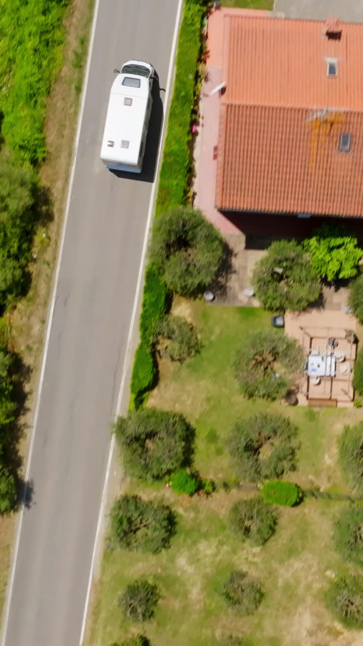 Vertical drone shot above a RV driving through a Tuscan town, sunjny day in Italy