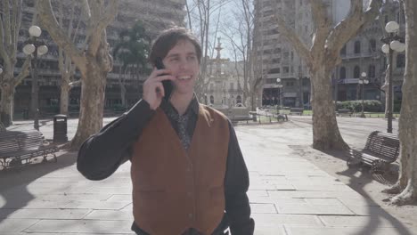 young man in shirt and tie speaks on cellphone and laughs cheerfully