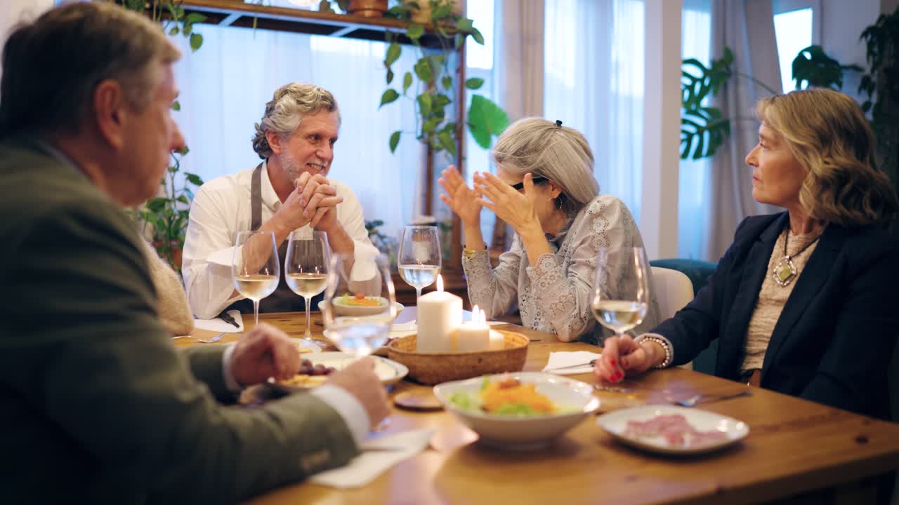 Happy Group of Mature Friends Enjoying Dinner and Conversation