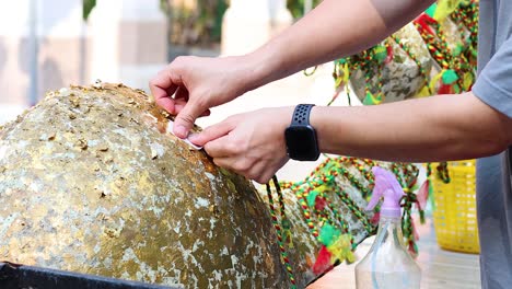 personas atando cuerdas coloridas en una piedra sagrada