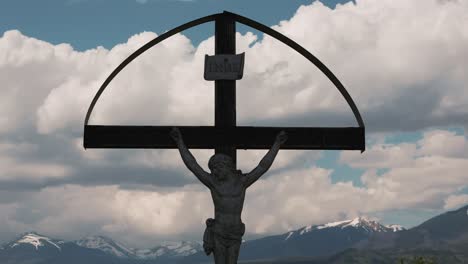 Statue-of-Jesus-on-cross-with-clouds-in-background-close-up