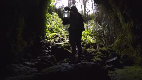 mujer sosteniendo una linterna en la entrada de una cueva