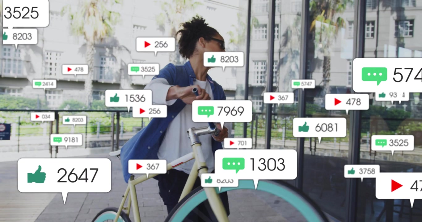 Man riding bike along glass facade, stopping to check phone for likes, spawning social media icons