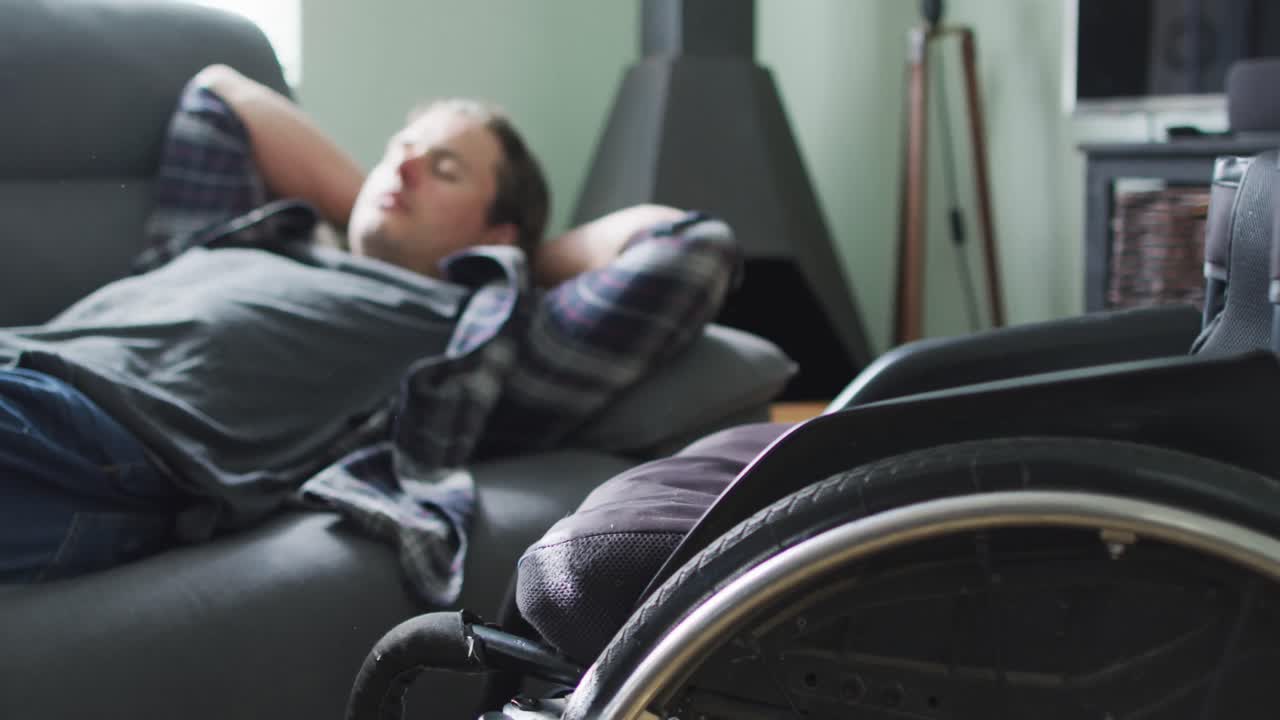 Relaxed caucasian disabled man lying on sofa in living room