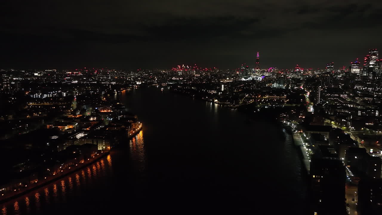 Aerial view following the Thames river with London skyline backdrop, night in UK