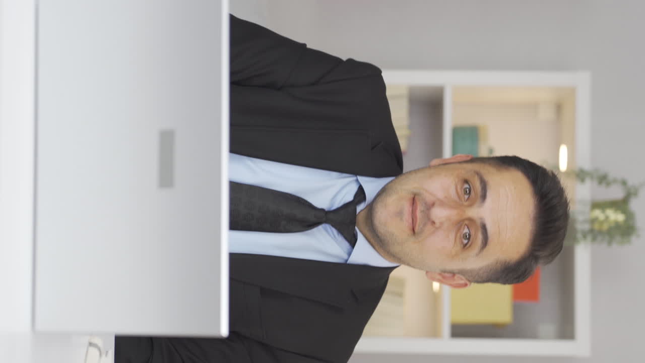 video vertical de un trabajador de oficina en casa mirando a la cámara con emoción y sintiéndose feliz.