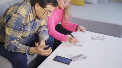 una pareja seria, marido y mujer, están planeando el presupuesto de la casa, pagando facturas, calculando las finanzas.