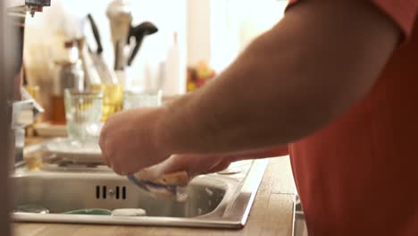 unrecognizable man cleaning the dishes at home