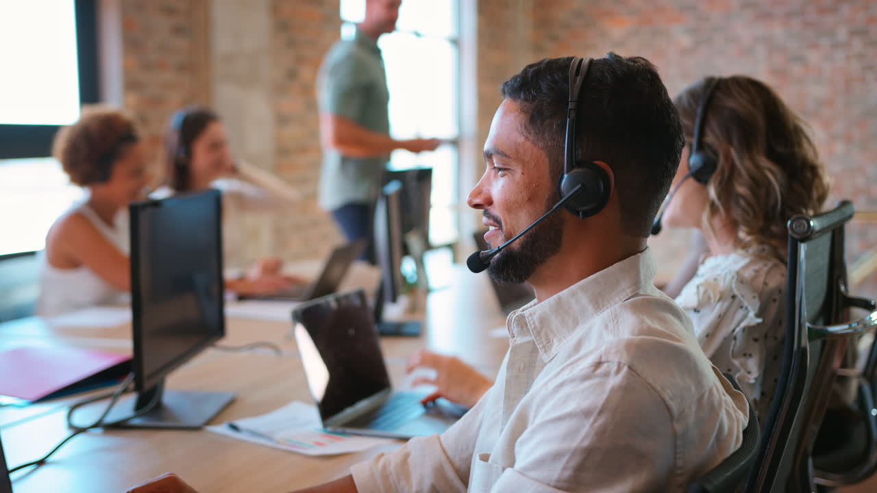 Portrait Of Businessman In Multi-Cultural Business Team Wearing Headset In Customer Support Centre