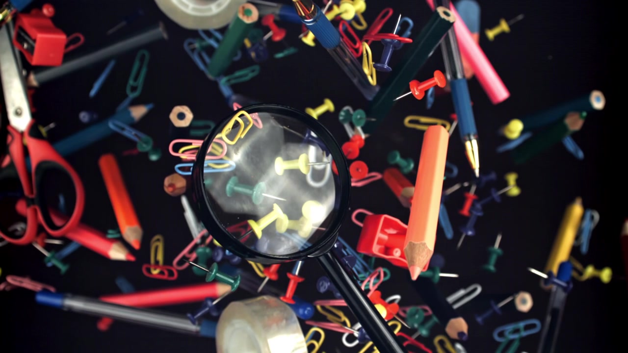 Magnifying Glass and Colorful Stationery Floating in Slow Motion
