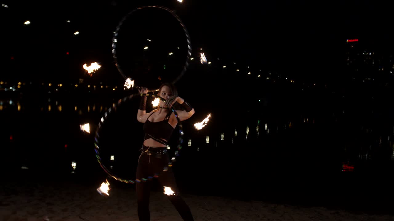 bonita chica de fuego girando en llamas hula hoops al aire libre