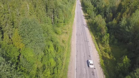 aerial view of a country road through a forest with a car