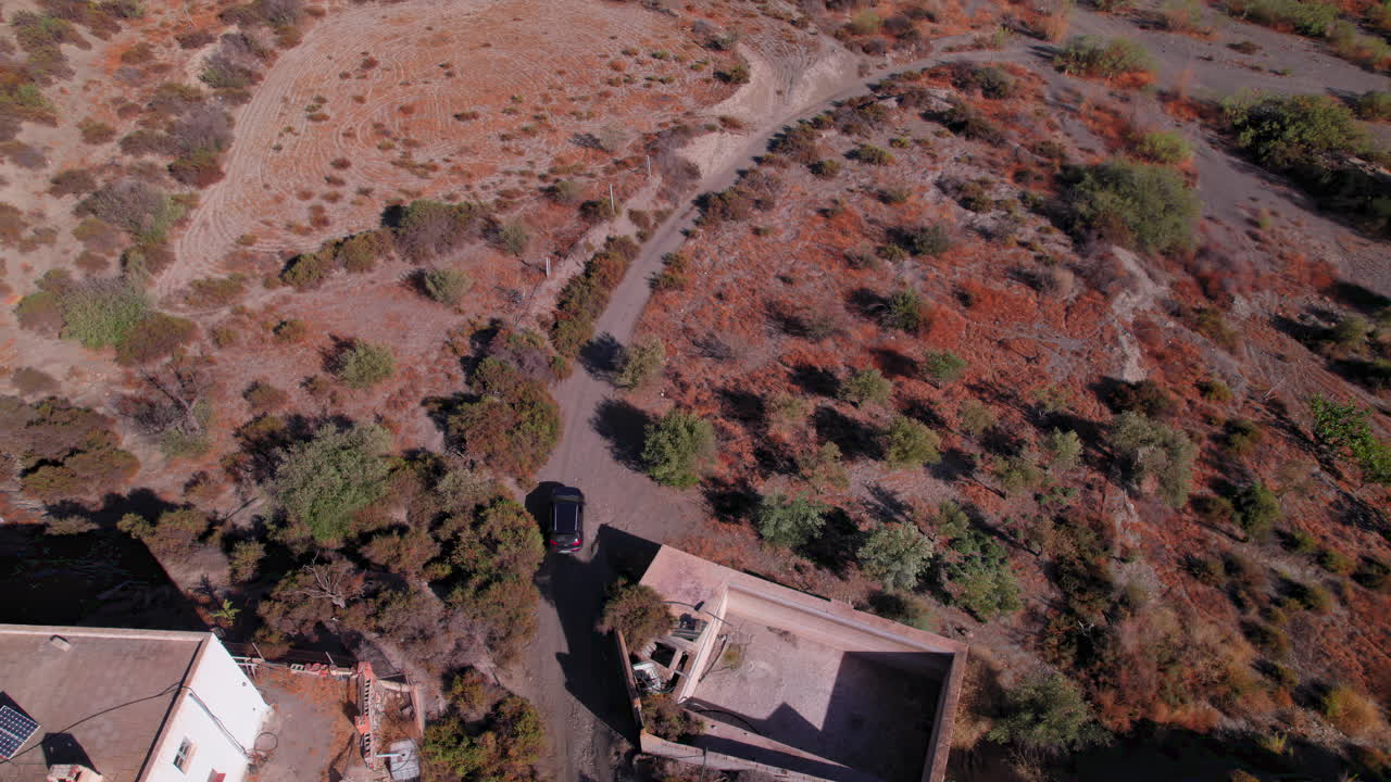 Car going trough a dirt road in Tabernas desert, Spain, aerial birdseye view