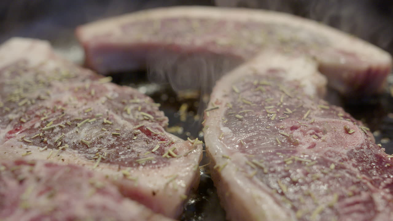 Sizzling lamb chops with seasoning in cast iron frying pan, close-up dolly