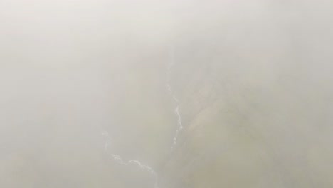 nubes que se separan revelando una cascada alta y un cañón verde en islandia cañón mulagljufur