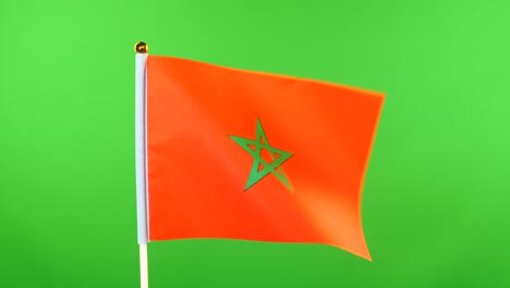 flag of morocco on flagpole on green background. moroccan flag waving in wind.