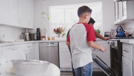 pre-teen hispanic boy baking with his dad, high five and put cakes in the oven, close up