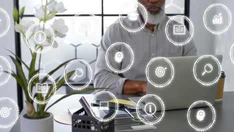 animación de múltiples iconos sobre un hombre afroamericano trabajando en una computadora portátil en la oficina