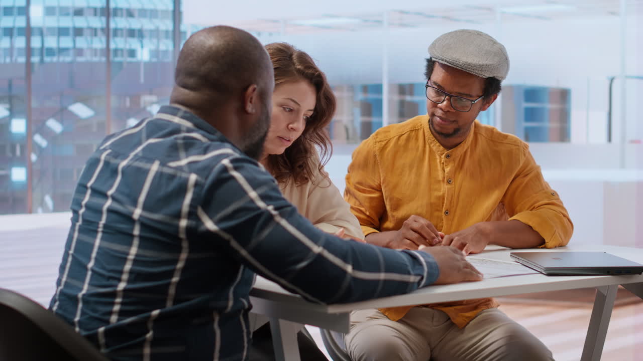 Ejendomsmægler præsenterer tegninger for en iværksætter på en kontortur