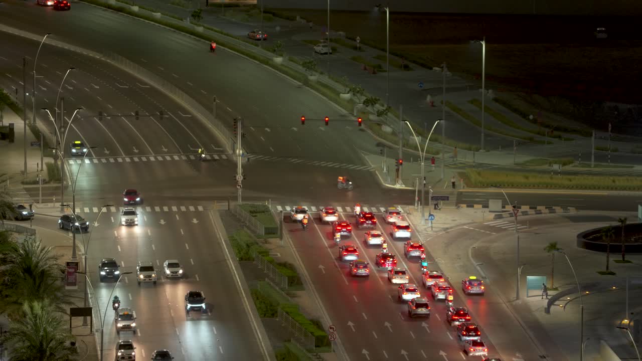 Looking down at an isolated, busy, city, nighttime intersection, crossroad, or junction in Abu Dhabi, United Arab Emirates on a hot and muggy, humid night