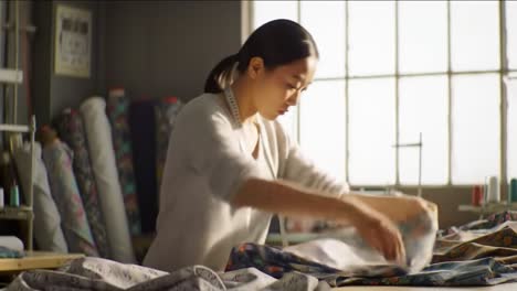 a skilled individual meticulously arranges vibrant fabrics in a well-lit sewing studio, showcasing attention to detail and creativity in design. the atmosphere is inspiring and lively.