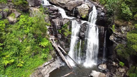 drone pans out to reveal magnificent waterfall set in tropical rainforest