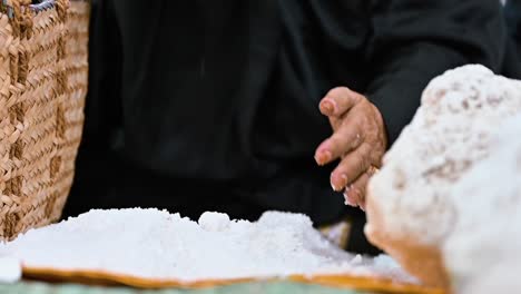 una mujer árabe pulverizando la sal marina a mano, tradicionalmente usando una roca