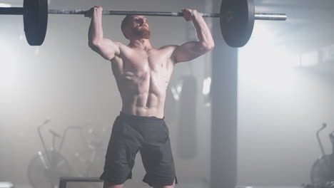 handsome muscular man does deadlift and curls with a heavy barbell. athletic shirtless man training doing power strength and endurance exercises with barbell. workout in the hardcore gym