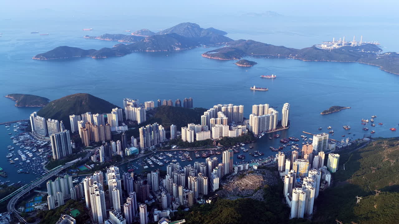 Cinematic aerial view of Hong Kong skyline shrouded in mist at blue hour, with glowing skyscrapers and Victoria Harbour fading into a moody, atmospheric twilight