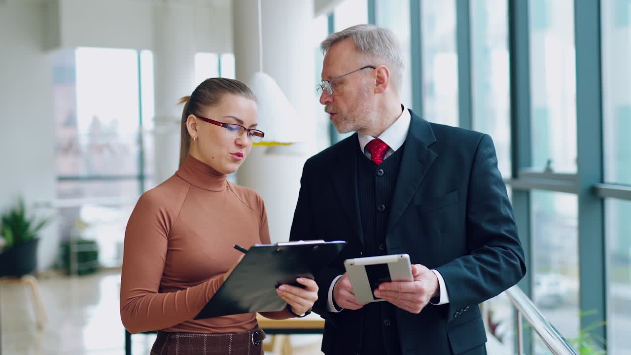 Mature businessman and female secretary. Senior entrepreneur in elegant costume talking to a beautiful woman in modern office.