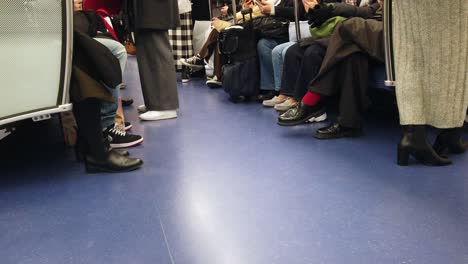 pov zu füßen aus dem inneren eines u-bahn-pendlerzugs in tokio, japan, mit vielen passagieren darin