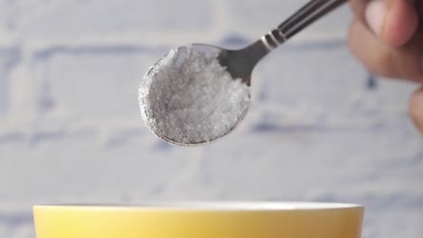 sugar being poured into a bowl