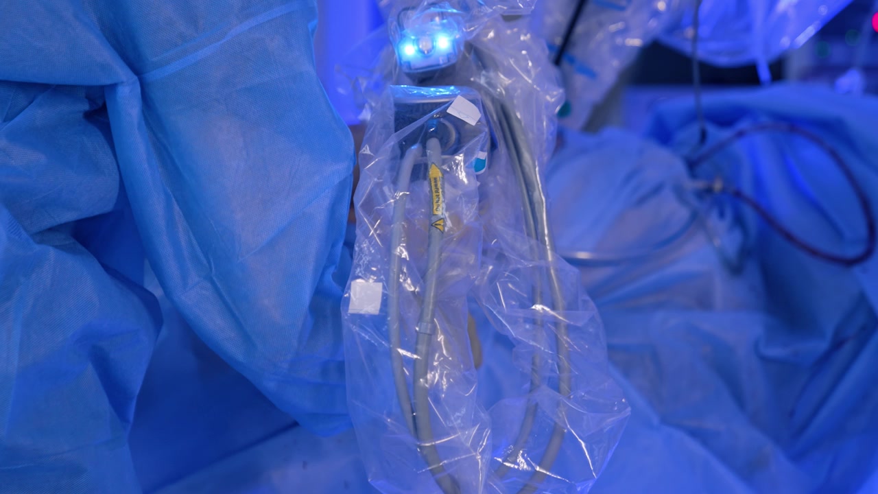 Medico in camice blu lavora vicino al braccio robotico del sistema chirurgico Da Vinci. Microchirurgia eseguita in un ospedale moderno.