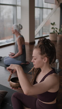 women meditating with singing bowls in yoga studio